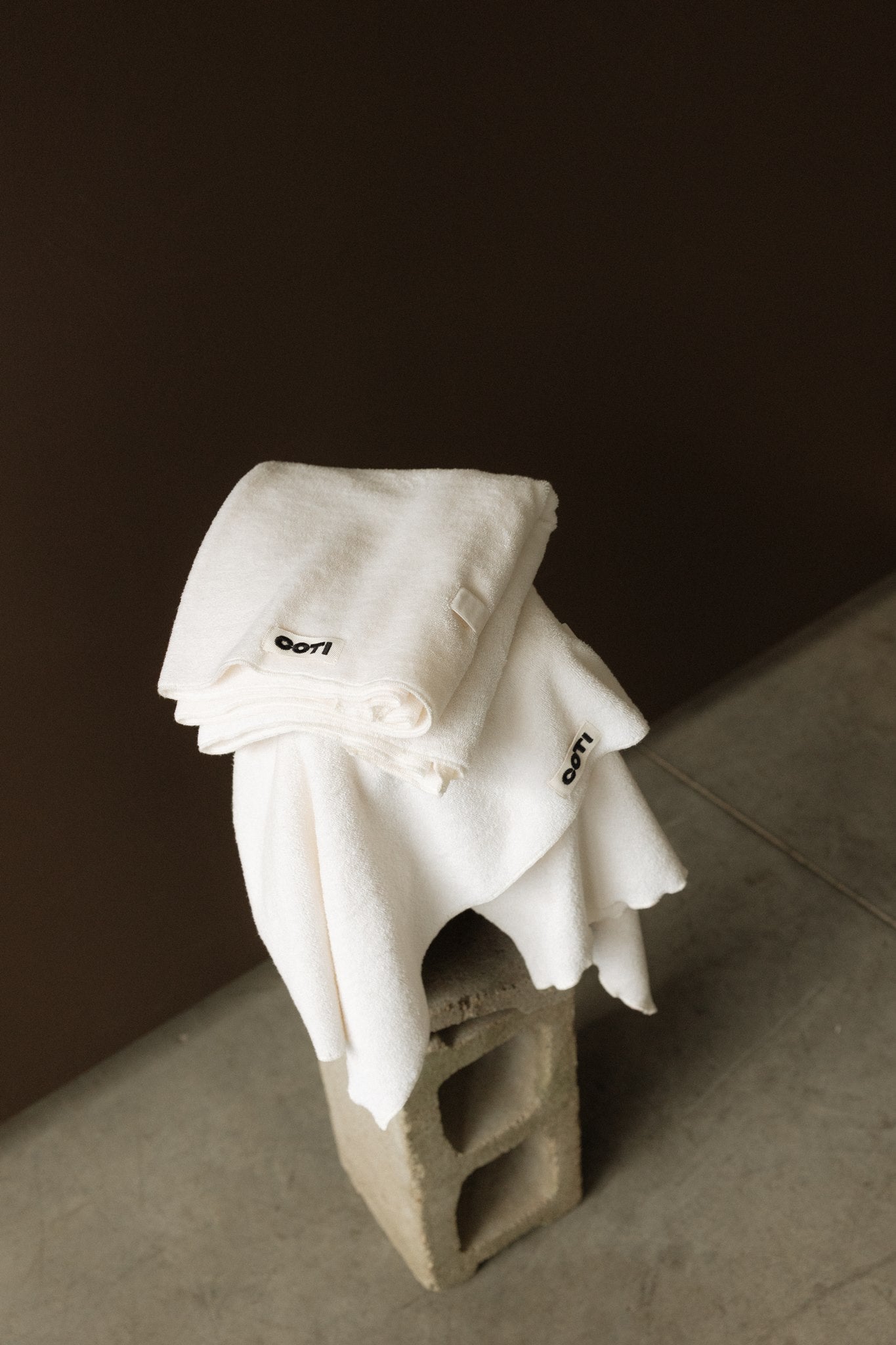 Cream COTI hair towel draped over a cinder block.